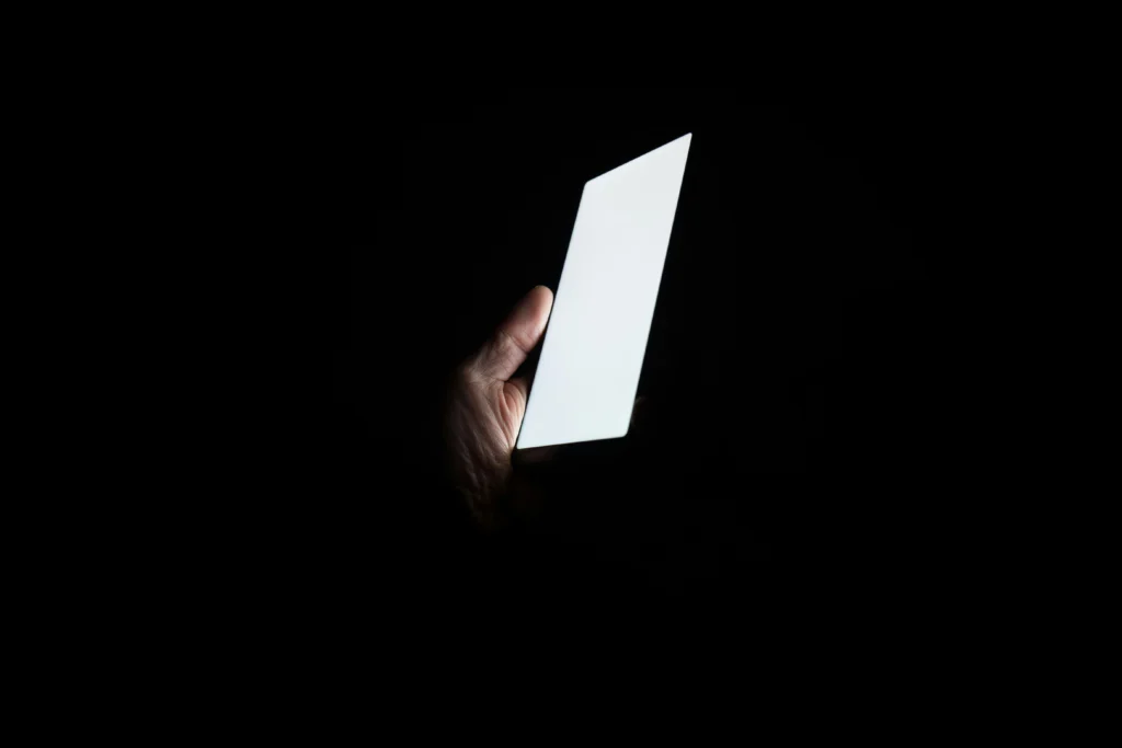 暗闇の中でスマートフォンを持っている人。（画像提供：Andrew Guan、Unsplash）