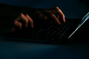 暗い環境でパソコンでタイピングしている人。（画像提供：Moritz Kindler、Unsplash）